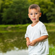 little latin boy looking curiously while standing with a fishing lake in the background - PhotoDune Item for Sale