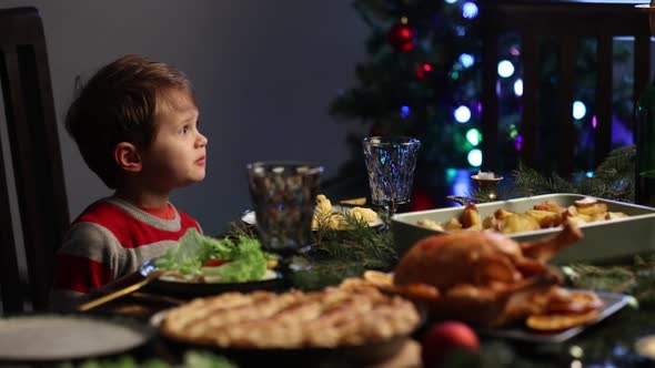 Little boy stay near Christmas dinner table with food