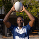 African American young male athlete holding rugby ball above head on field outdoors - PhotoDune Item for Sale