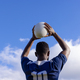 African American young male athlete holding white rugby ball above head on field, copy space - PhotoDune Item for Sale