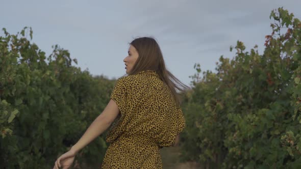 Happy Woman Dancing In Vineyard With Glass Of Wine