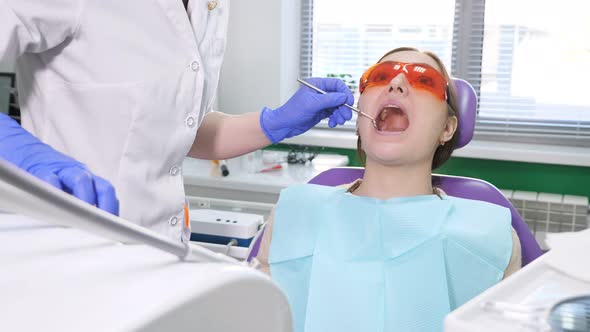 Dentist Treating Teeth to Woman Patient in Clinic alt