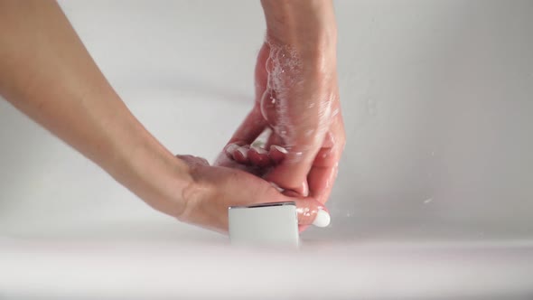 hand of beauty woman wash your hands at the wash basin with foam, cleanse the skin. Top view. alt