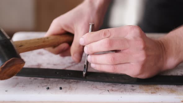 The Leather Craftsman Is Making Holes in a Hand-made Belt alt