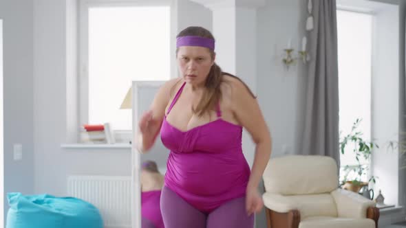 Medium Shot Portrait of Funny Overweight Caucasian Woman Running in Place Looking at Camera alt