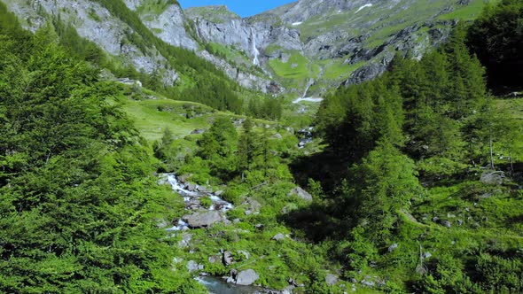 Aerial: drone flying over scenic waterfall and mountain stream on the italian Alps alt