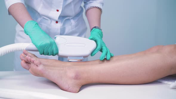 Cosmetologist Does Laser Epilation on Client Leg in Salon alt