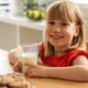 Cheerful girl enjoying fresh milk and homemade cookies, perfect for a wholesome snack time. - PhotoDune Item for Sale