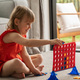 Cute little girl strategizing in Connect Four. Logic game - PhotoDune Item for Sale