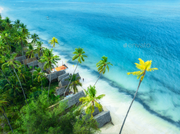 Aerial view of palms, bungalows, sandy beach, sea with waves - Stock Photo - Images