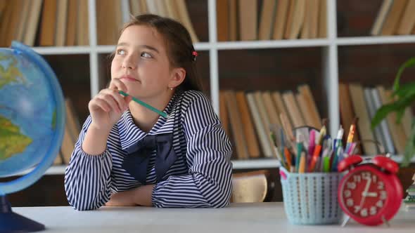 schoolgirl sitting at table desk at library or home meditates doing homewor