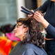 Woman sitting in hair salon while hairstylist ironing the hair - PhotoDune Item for Sale