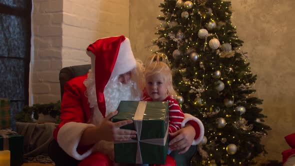 Kind Santa Claus Giving Gift Box To Little Girl