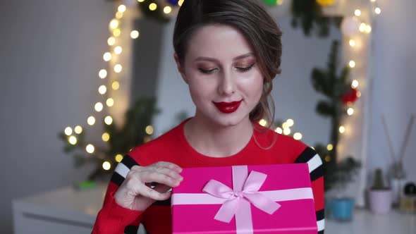 Young woman in rd sweater open gift box