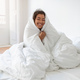 Smiling Woman Wrapped in Blanket on Bed - PhotoDune Item for Sale