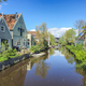 A dutch canal with wooden houses a lush, green countryside with vibrant foliage and rolling hills - PhotoDune Item for Sale
