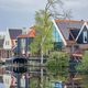 A picturesque scene of a charming row of houses lined up next to a peaceful body of water, creating - PhotoDune Item for Sale