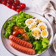 Plate with sausages, egg sandwich, tomatoes and lettuce leaves on the table vertical view - PhotoDune Item for Sale