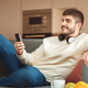Man Sitting on Couch Holding Cell Phone at Home - PhotoDune Item for Sale