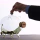 Saving Money - a Businessman Hoards Cash and Throws Some Coins Into a Glass Piggy Bank - VideoHive Item for Sale