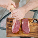 Top view of unrecognizable man using hand mill to season raw strip steak with salt - PhotoDune Item for Sale