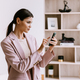 Focused professional woman in pink blazer using smartphone in modern office, embodying efficiency an - PhotoDune Item for Sale