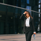 Sophisticated businesswoman walking confidently near glass buildings, looking slightly away - PhotoDune Item for Sale