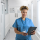 Portrait Of Smiling Female Nurse Wearing Scrubs In Hospital Corridor With Digital Tablet - PhotoDune Item for Sale