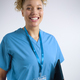 Studio Portrait Of Smiling Female Nurse Wearing Scrubs With Digital Tablet Against Grey Background - PhotoDune Item for Sale