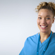 Studio Portrait Of Smiling Female Nurse Wearing Uniform With Security Lanyard On Grey Background - PhotoDune Item for Sale