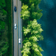 Aerial view of road between green tree forest and blue lake sea water in Finland - PhotoDune Item for Sale