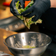 close-up in a professional kitchen the chef mixes lettuce leaves with sauce with his hands - PhotoDune Item for Sale