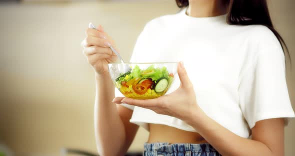 Pretty Asian Woman Eats a Salad of Fresh Vegetables