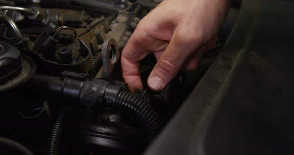 Hands of mechanic checking a car engine alt