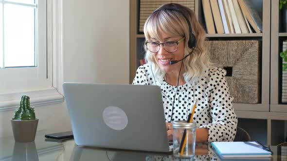 Modern pretty woman work at home in video conference call with laptop computer and headphones alt