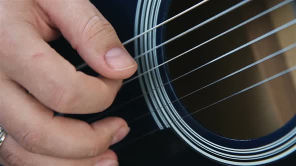 Musician Plays Strings With His Fingers On An Acoustic Guitar