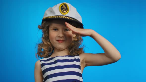 Little Curly Sailor Girl Puts Her Hand to the Cap and Smiles in the Studio alt