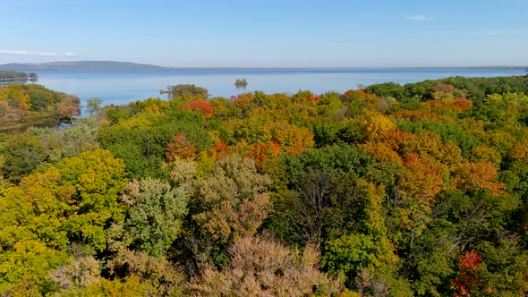 4K camera drone vertical climb above tree tops, beautiful fall colors and river view.