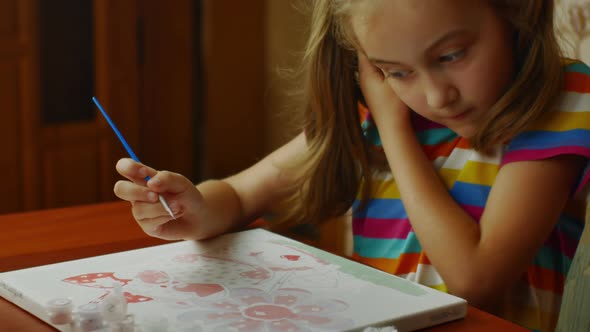 A Little Girl Enthusiastically Paints with Paints on a White Canvas