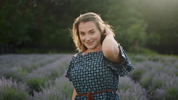 Attractive Curly Brunette Woman Walking Among Lavender Bushes White Happy Looking at Camera Dancing