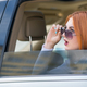 Young woman with red hair and sun glasses travelling by car. - PhotoDune Item for Sale