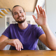 Caucasian young man sitting at table, waving hello at home on a video call - PhotoDune Item for Sale