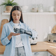 Woman with a robotic arm examines its functionality in a cozy kitchen setting. - PhotoDune Item for Sale