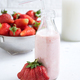 Glass bottle beside a cup filled with strawberries - PhotoDune Item for Sale