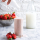 Hand pouring strawberry milk into a transparent container of ice cream - PhotoDune Item for Sale