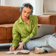 Young Woman Wearing Headphones While Writing Notes and Using Laptop - PhotoDune Item for Sale