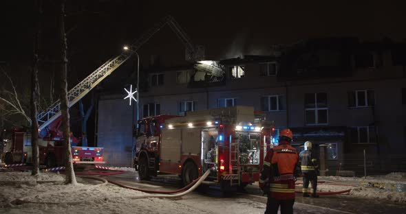 Firefighters Put Out Fire in Burning Apartment House at Night alt