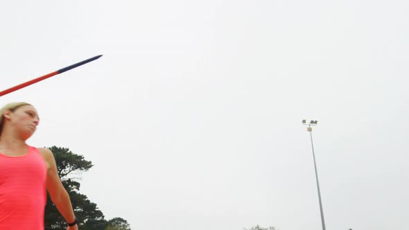 Low angle view of Caucasian female athlete practicing javelin throw at sport venue 4k alt