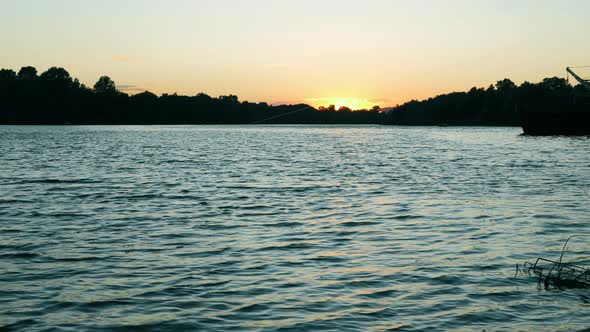 A beautiful view of the waves of the river and the forest in the rays of the sunset. Nice evening