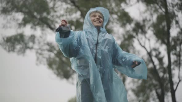 Portrait of Happy Joyful Caucasian Boy Jumping and Cheering Rain Outdoors alt